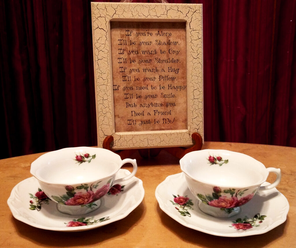 Two teacups on saucers in front of placard with dark background