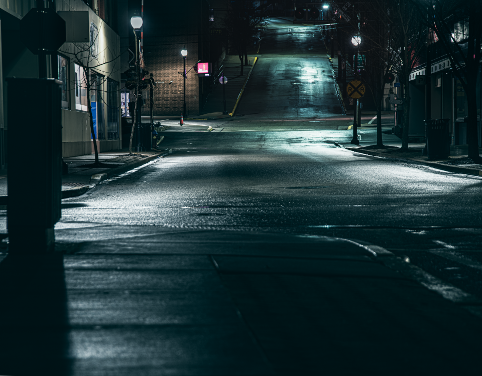 Dark street at night, a few small lights shining