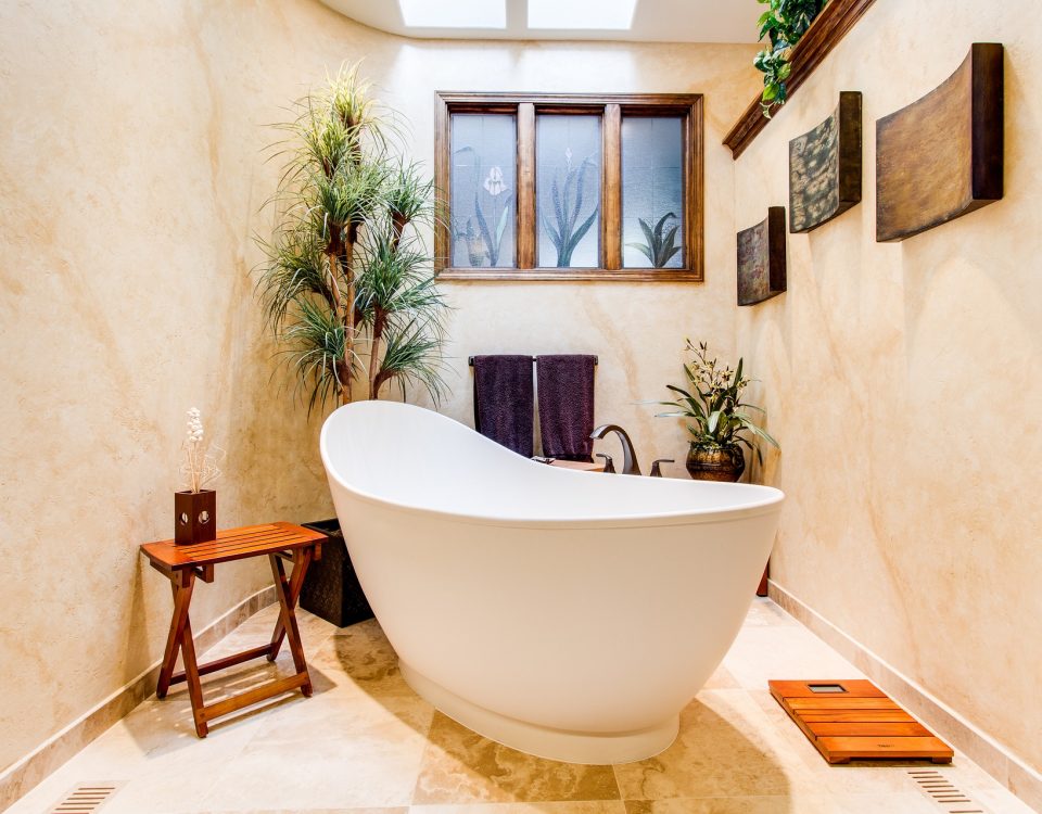 bathtub in lovely bathroom, live plants, table with candle and window visible