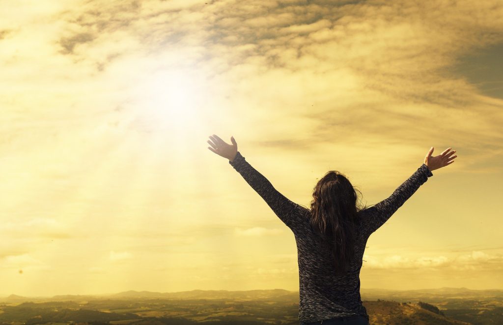 Reaching goals - Woman with arms held high to the sun